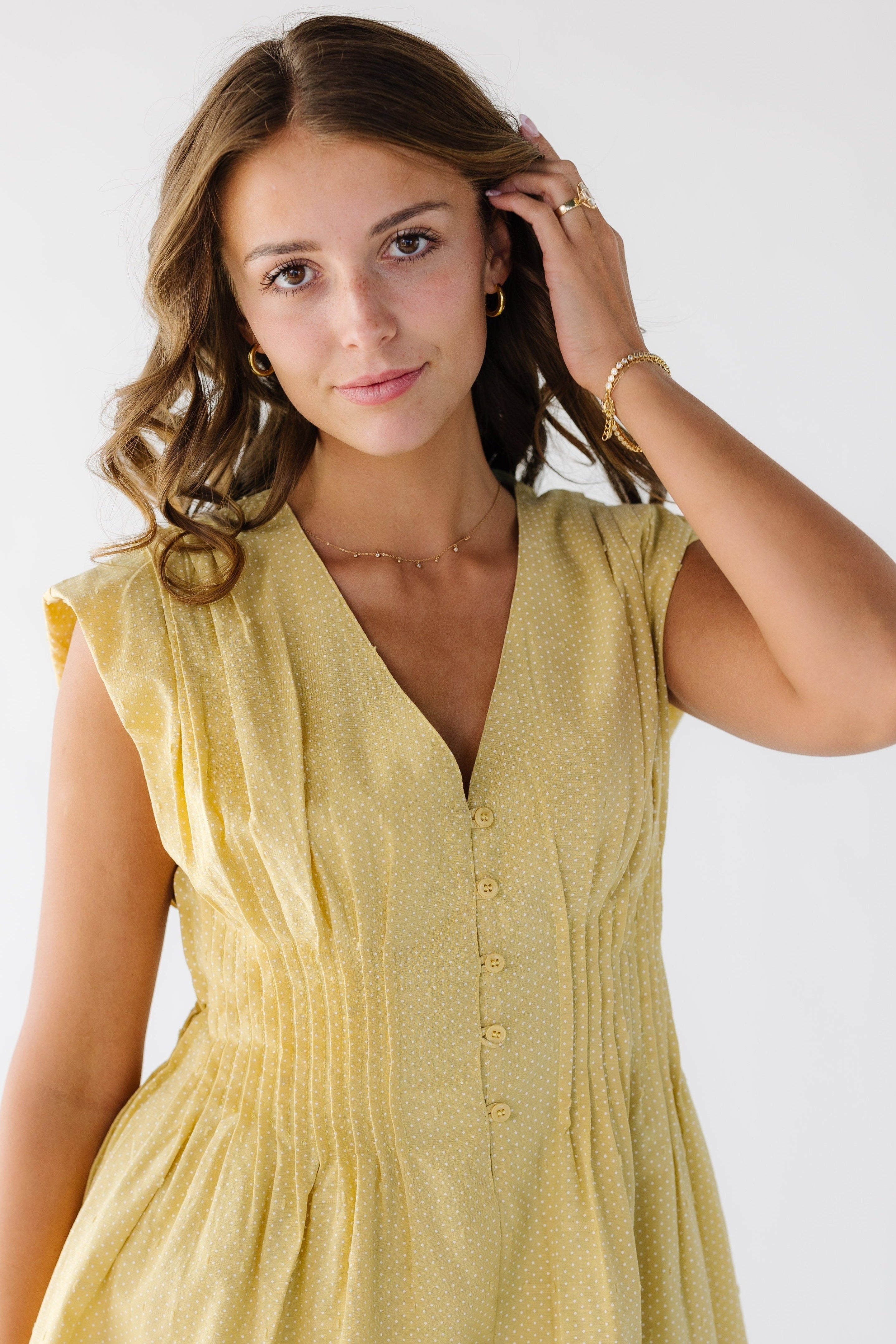 CloseviewofayoungwomanwearingayellowandwhitedotsleevelessdresswithaV-neckline_andpleatsallaroundthewaist.jpg The Penelope Dress
