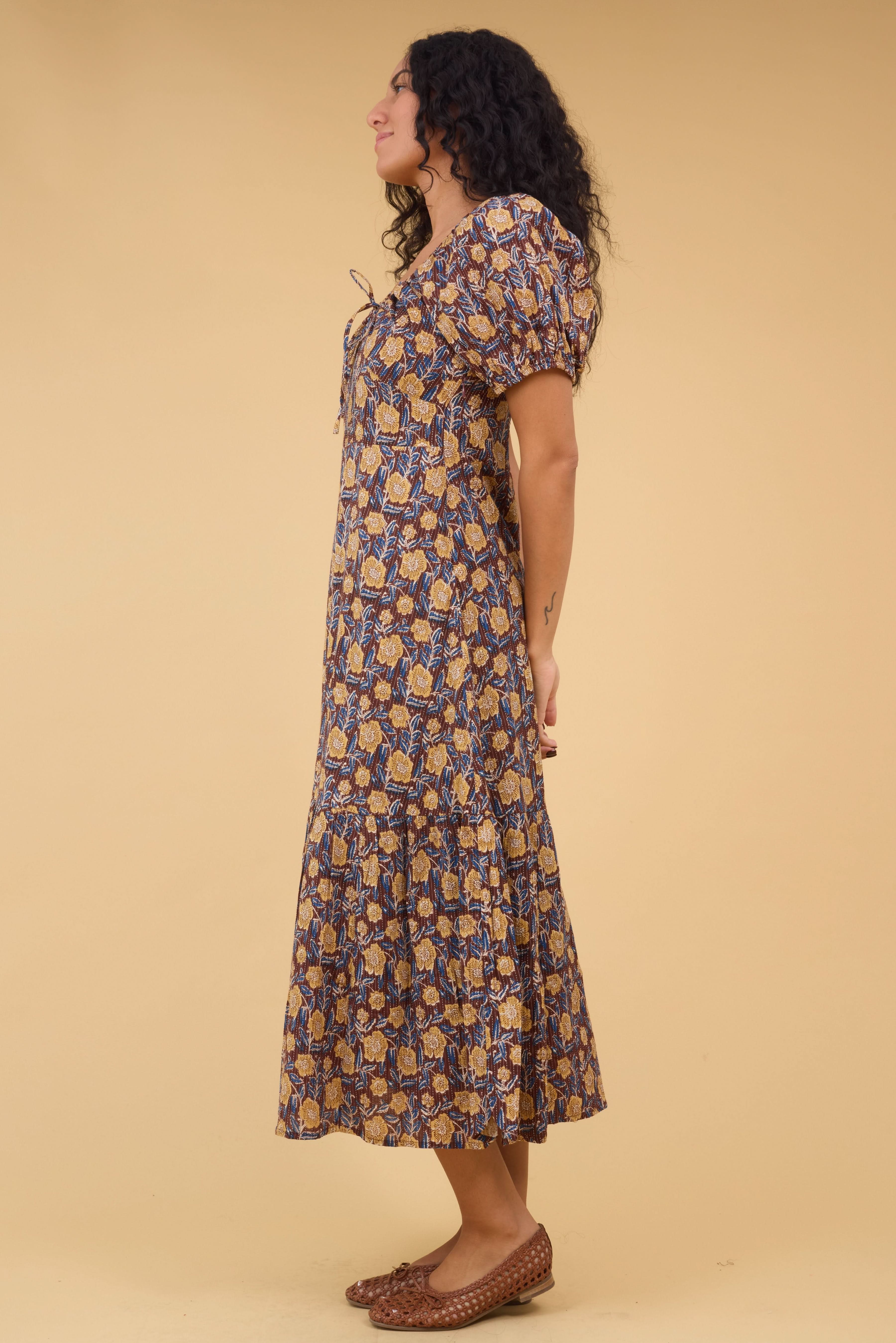Side_view_of_a_woman_wearing_a_brown_floral_dress_with_a_wide_bottom_ruffle_and_short_puff_sleeves.jpg Citrus Alba Dress