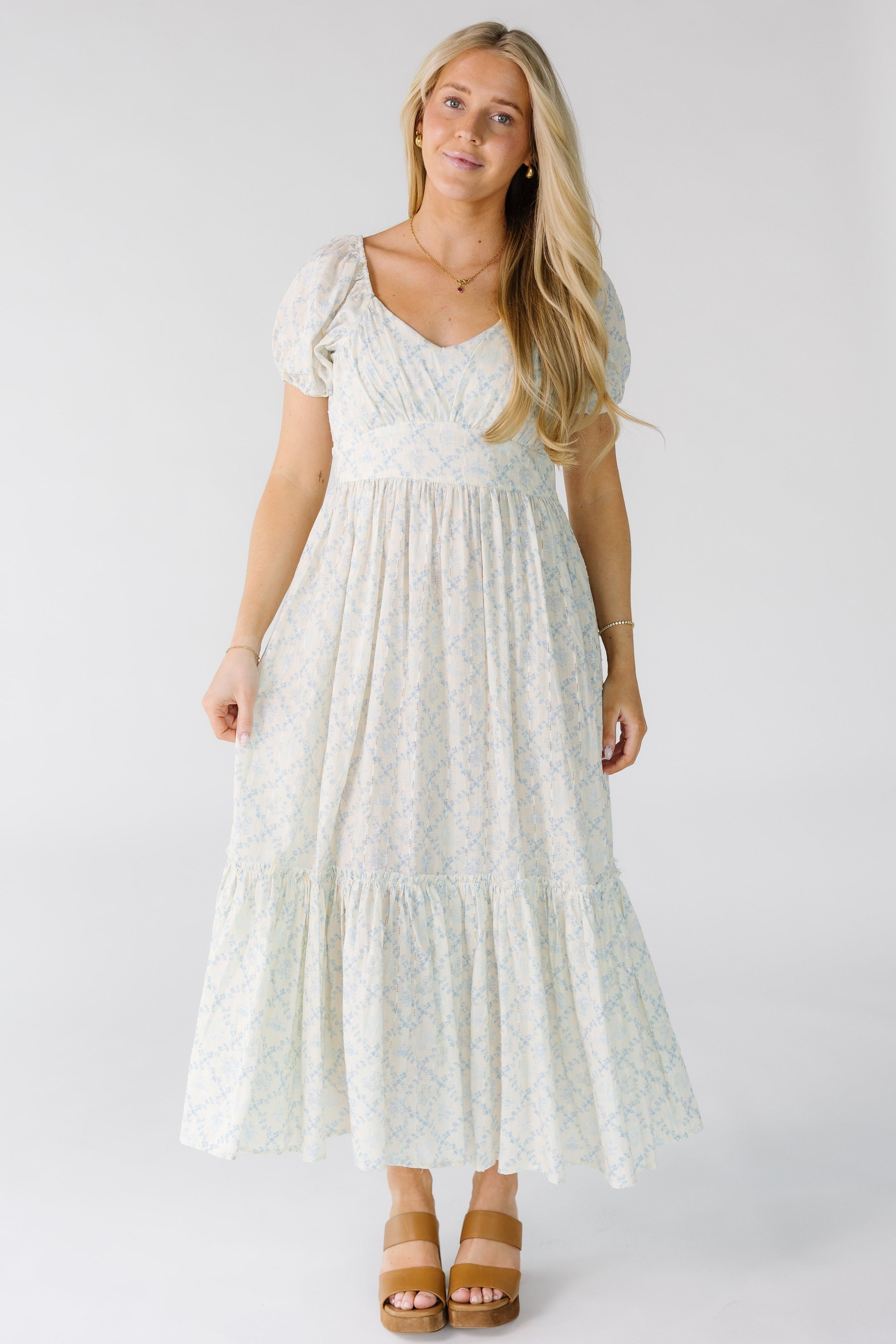 Womanwearingamodestwhiteandbluefloralmididresswithasweetheartnecklineandshortpuffsleeves._7c9eef36-58f5-442f-b7fe-d5a3fc64afaa.jpg Brass & Roe Swiss Midi Dress