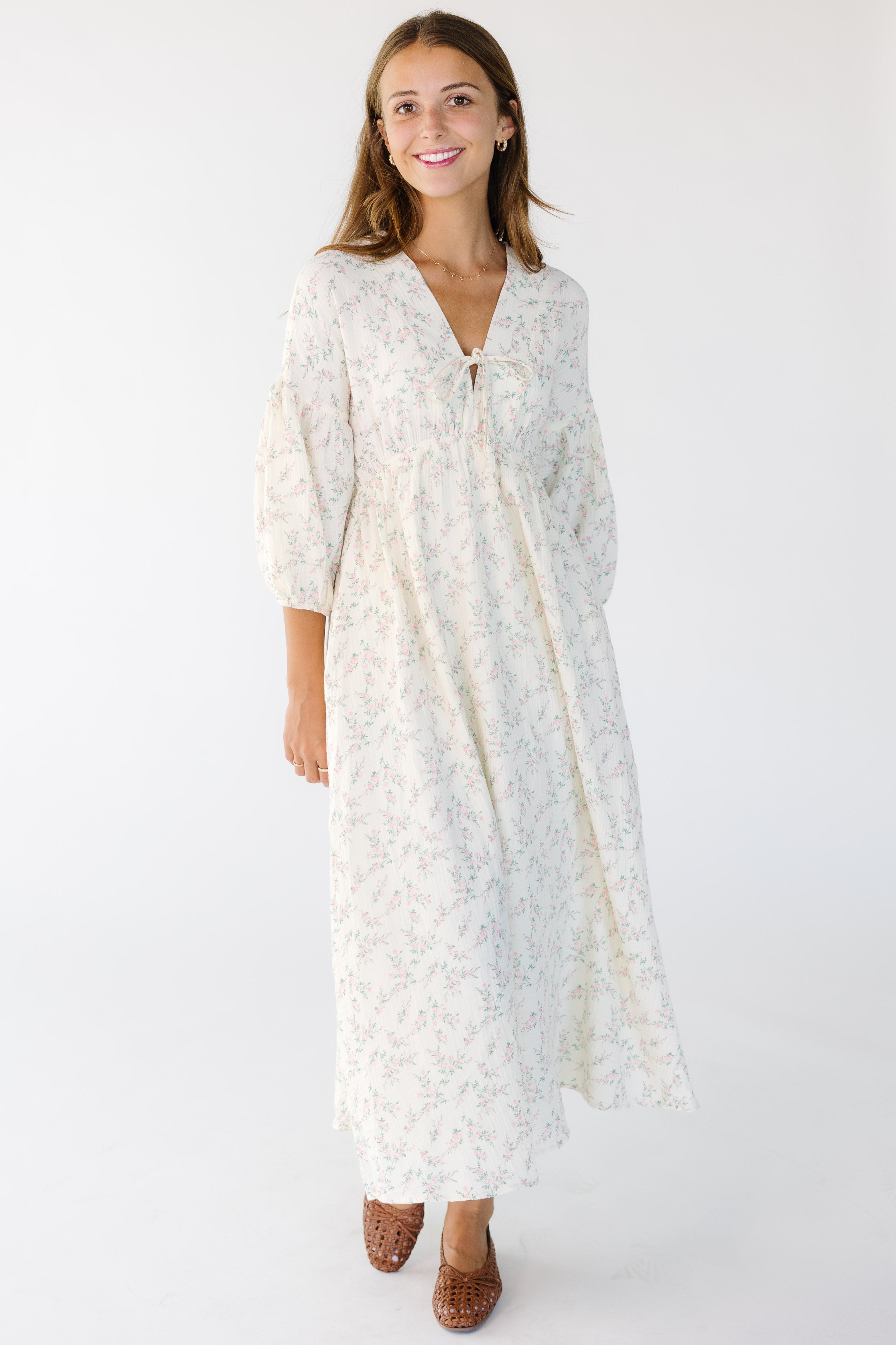 Young_woman_wearing_a_modest_cream_and_pink_floral_midi_dress_with_a_V-neckline_and_half_length_sleeves.jpg Brass & Roe A Gauze Tie Front Dress