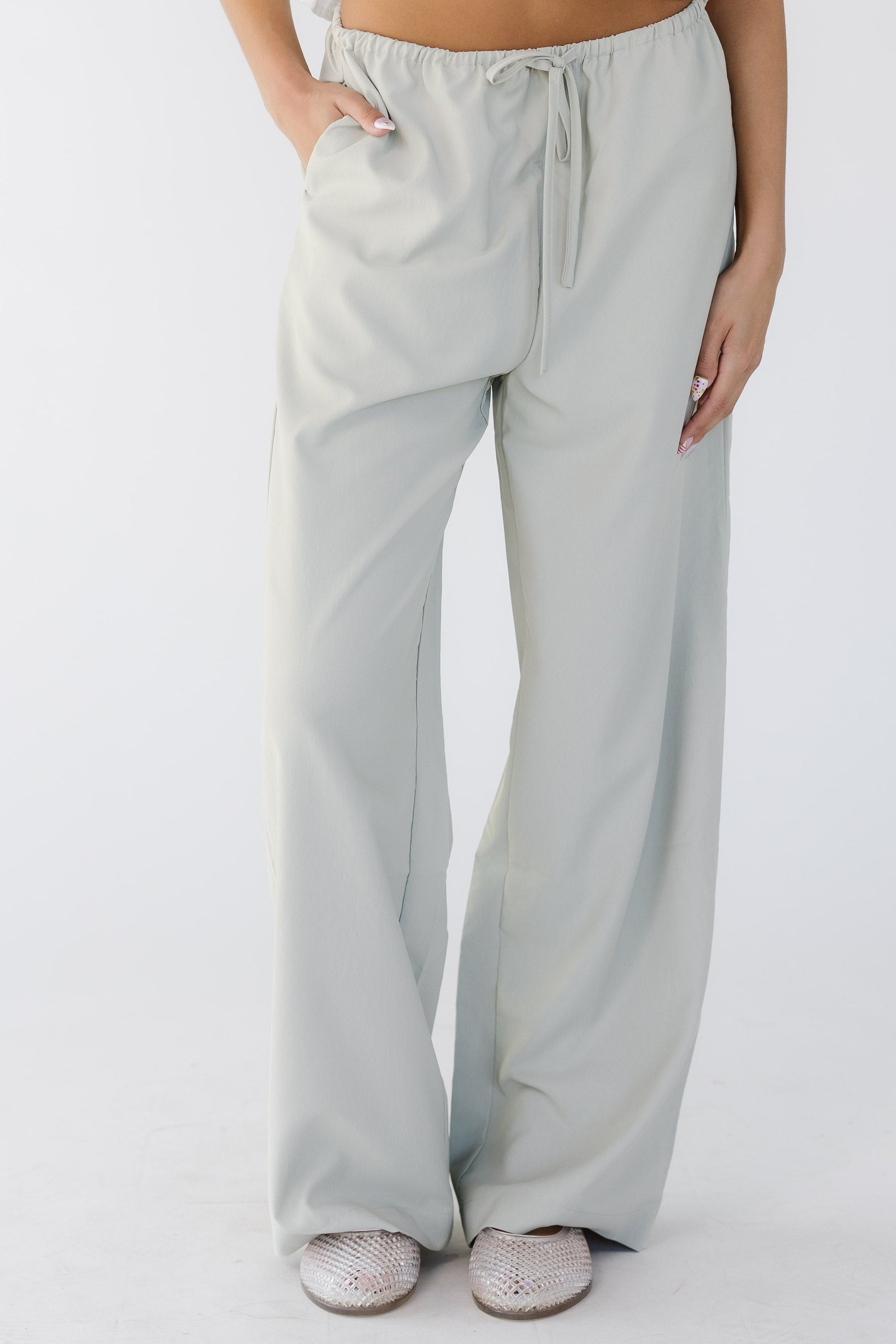 Young_woman_wearing_loose_fitting_grey_pants_cut_with_a_wide_leg_and_side_pockets.jpg The Evelyn Pants