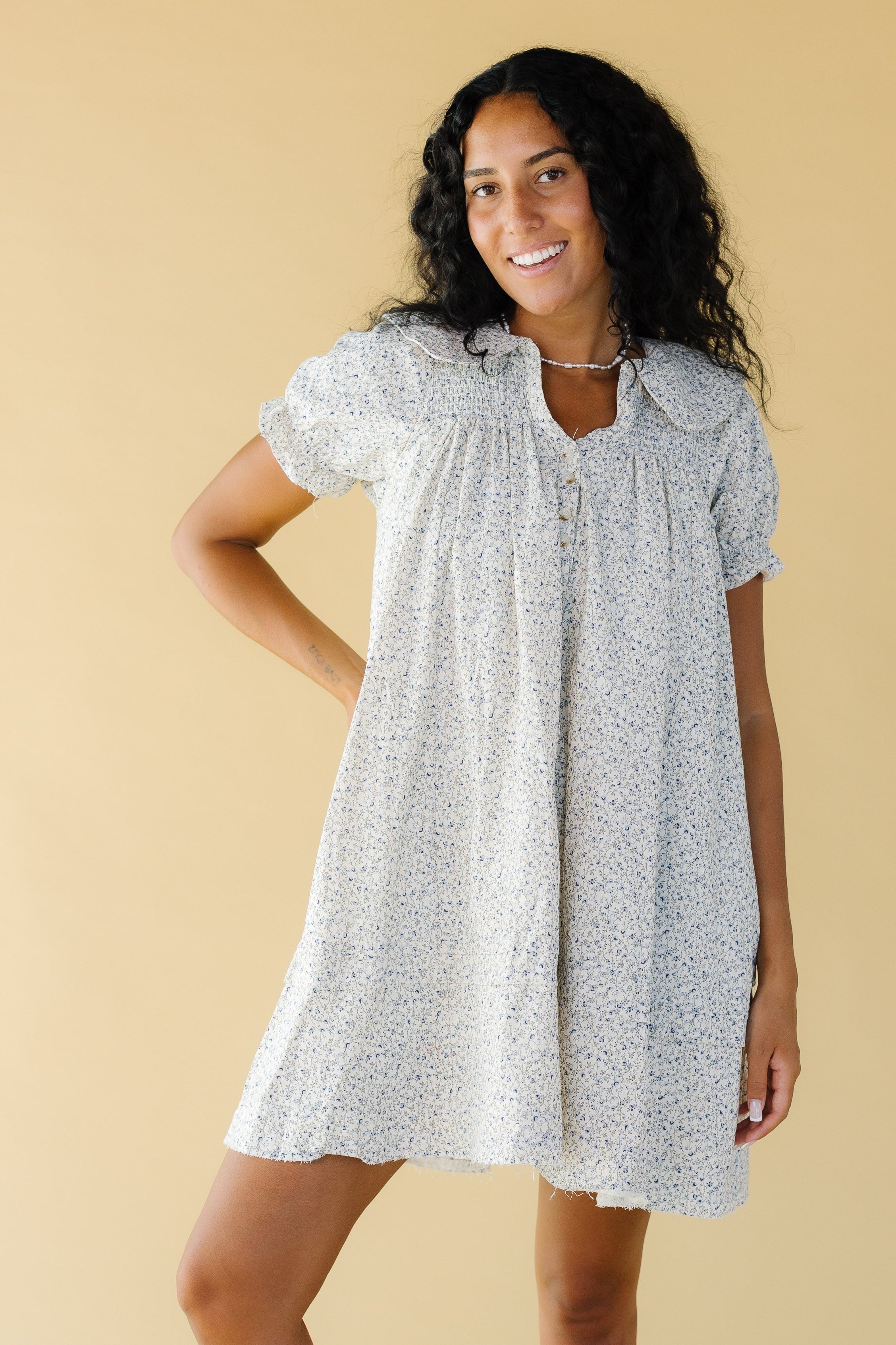 Youngwomanwearingacreamfloralprintdresswithsmockedfront_backyokewithshortsleeves.jpg Brass & Roe Collared Knee Dress
