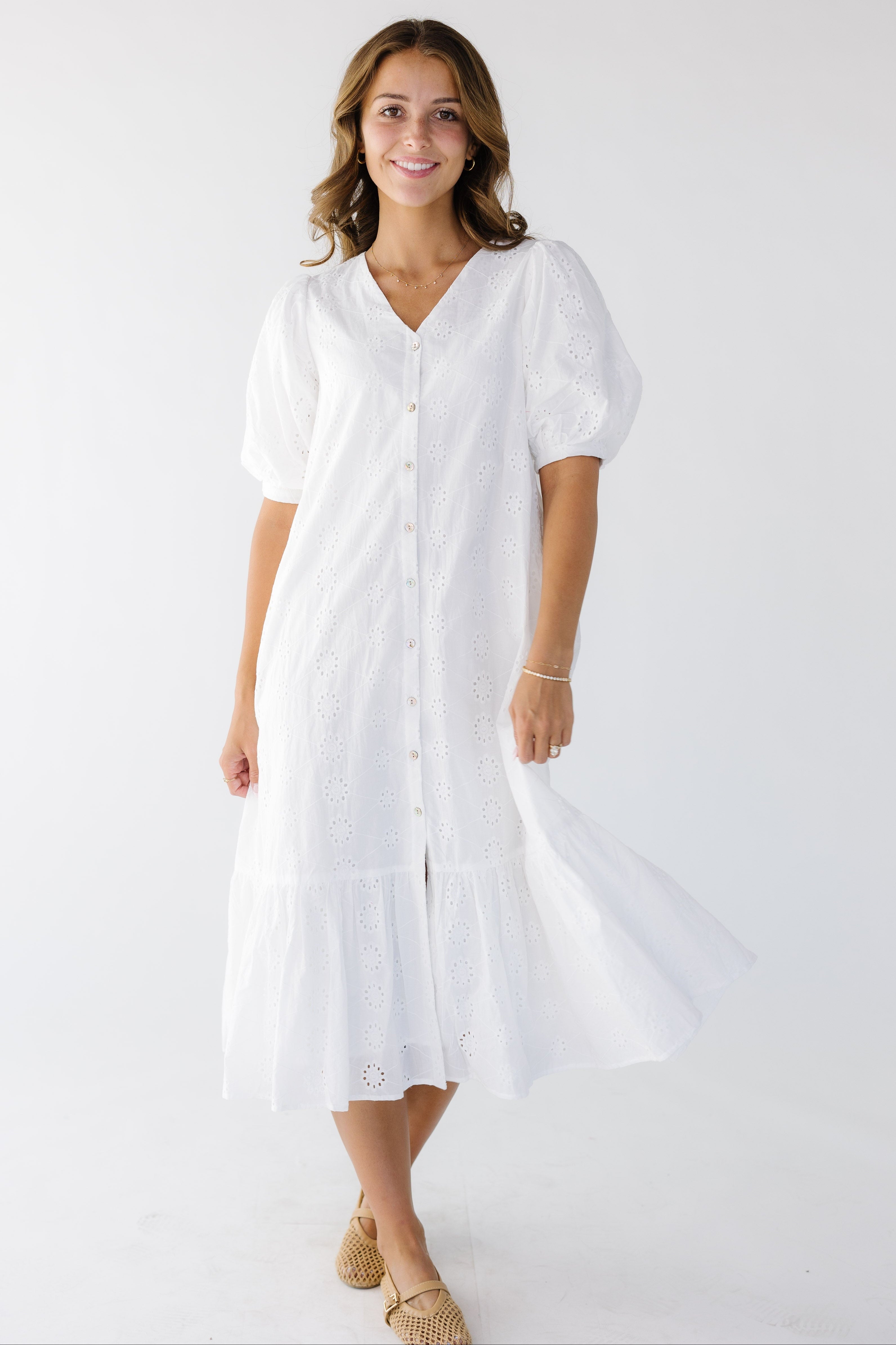 Youngwomanwearinganalleyeletdressinwhitewithav-necklineandwidebottomruffle.jpg Brass & Roe Cori Button Down Eyelet Dress